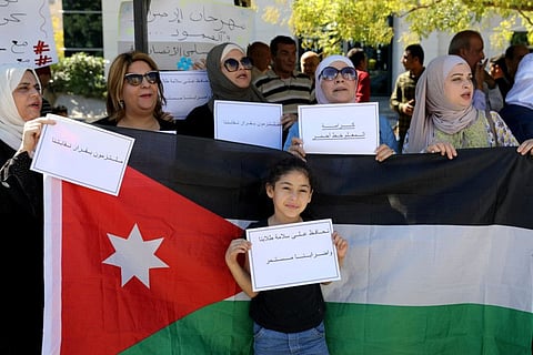 A girl holds placard in front of a Jordanian national flag as public schools' teachers take part in a protest in Amman, Jordan October 3, 2019.  