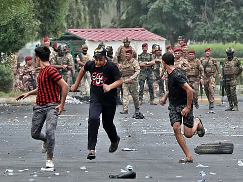Iraqi security forces chase anti-government protesters in Baghdad, Iraq, Sunday, Oct. 6, 2019. 
