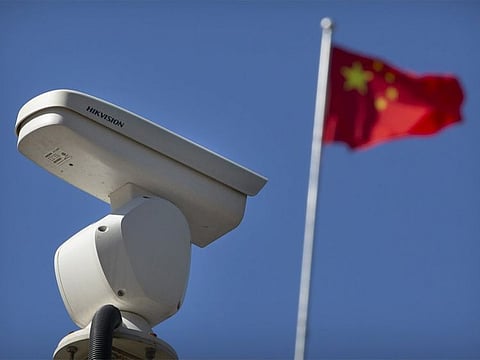 A Chinese flag flies near a Hikvision security camera monitoring a traffic intersection in Beijing, on October 8, 2019. The United States is blacklisting a group of Chinese tech companies that develop facial recognition and other artificial intelligence technology that the US says is being used to repress China's Muslim minority groups. 