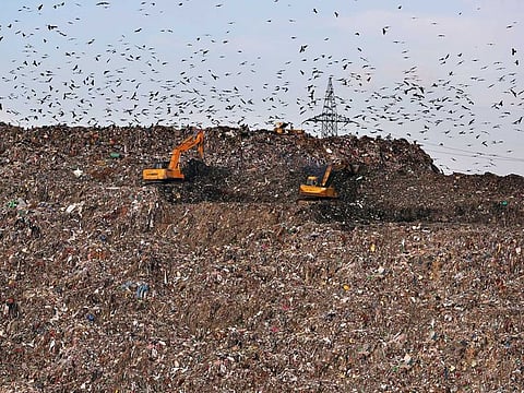 Land movers work on a mountain of garbage in the outskirts of New Delh. India is launching an ambitious campaign to eliminate single-use plastics within three years.