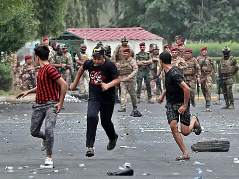 Iraqi security forces chase anti-government protesters in Baghdad on October 6, 2019. 