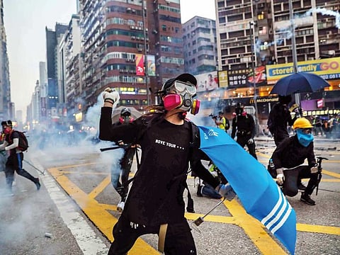 A protester throws back a tear gas canister fired by police in the Mongkok district in Hong Kong on October 20
