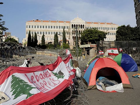 Lebanese protesters sleep in tents in front of the government headquarters, known as the Grand Serail building (background), in the heart of the capital Beirut on October 25, 2019 as anti-corruption demonstrators cut off major roads across the country for a ninth day, pledging to carry on with their protests despite the president offering to meet their representatives. 