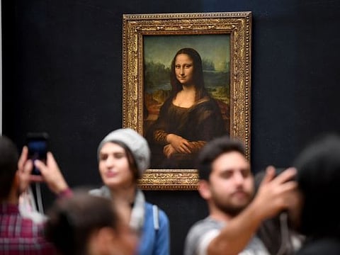(FILES) In this file photograph taken on October 7, 2019, visitors take photographs in front of The Mona Lisa (La Gioconda) after it was returned at its place at the Louvre Museum in Paris. The Louvre in Paris is putting the finishing touches to an ambitious Leonardo da Vinci retrospective opening on October 24, 2019, which groups more than 160 of the artist's works and has already attracted close to 200,000 advance visitor bookings. Timed to coincide with the 500th anniversary of the famed artist's death, the show, simply called "Leonardo da Vinci", took a decade to put together and includes works on loan from Queen Elizabeth and Bill Gates. - RESTRICTED TO EDITORIAL USE - MANDATORY MENTION OF THE ARTIST UPON PUBLICATION - TO ILLUSTRATE THE EVENT AS SPECIFIED IN THE CAPTION
 / AFP / ERIC FEFERBERG / RESTRICTED TO EDITORIAL USE - MANDATORY MENTION OF THE ARTIST UPON PUBLICATION - TO ILLUSTRATE THE EVENT AS SPECIFIED IN THE CAPTION