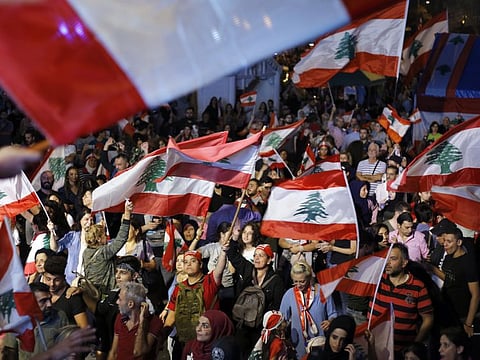 Anti-government protesters hold national flags during ongoing protests against the Lebanese government, in Beirut, Lebanon.
