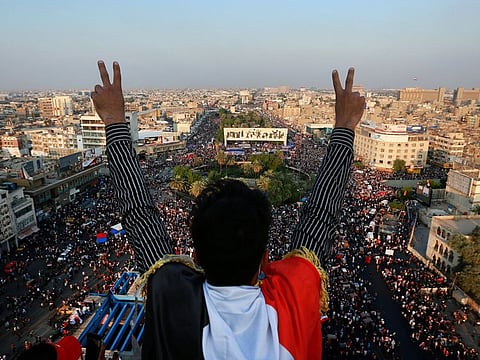 A protester flashes the victory sign while anti-government protesters gather in Tahrir Square during ongoing protests in Baghdad, Iraq, Friday.