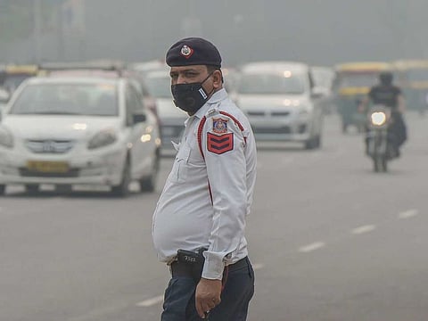 A traffic policeman wearing an anti-pollution mask diverts traffic in New Delhi 
