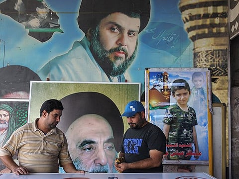 Iraqi men work in front of posters bearing the portraits of Iraqi Shiite cleric and political leader Moqtada al-Sadr (top), Grand Ayatollah Ali Sistani (C), and Imam Ali, the cousin of Prophet Mohammed, in the capital Baghdad's eastern Sadr City district on October 24, 2019.