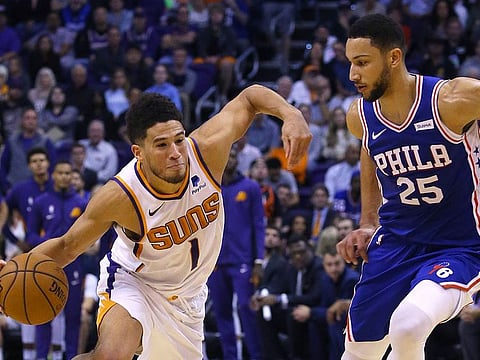 Phoenix Suns guard Devin Booker drives past Philadelphia 76ers guard Ben Simmons during the second half of an NBA basketball game Monday, Nov. 4, 2019, in Phoenix.  The Suns defeated the 76ers 114-109.