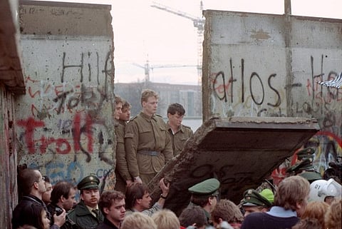 In this November 11, 1989 file photo, East German border guards are seen through a gap in the Berlin wall after demonstrators pulled down a segment of the wall at Brandenburg gate, Berlin.