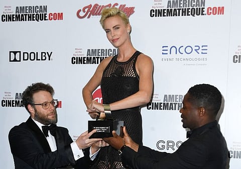 US/Canadian actor Seth Rogen (L) and British actor David Oyelowo (R) present US/South African actress Charlize Theron with the 2019 American Cinematheque award during the 33rd Annual American Cinematheque Awards Gala at the Beverly Hilton hotel in Beverly Hills on November 8, 2019. / AFP / VALERIE MACON
