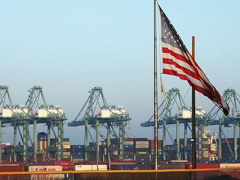 An American flag flies with shipping containers stacked at the Port of Los Angeles in the background, which is the nation's busiest container port in San Pedro, California.