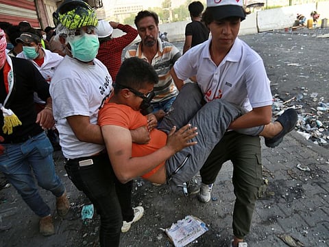 An injured protester is rushed to a hospital during clashes between Iraqi security forces and anti-government protesters in downtown Baghdad, Iraq, Sunday, Nov. 10, 2019. (AP Photo/Khalid Mohammed)