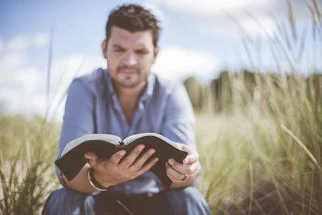 Opn Man reading book outdoors-1573641365581