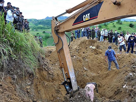File photo: A backhoe lifting a dead body from a shallow grave, a victim of a massacre after gunmen shot at least 22 people in Ampatuan town, Maguindanao province.