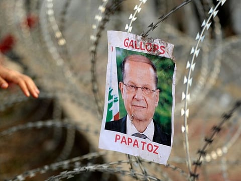 A picture of Lebanese President Michel Aoun hangs on barbed-wire on the road leading to the Presidential Palace in Baabda, on the eastern outskirts of Beirut on November 13, 2019, nearly a month into an unprecedented anti-graft street movement. 