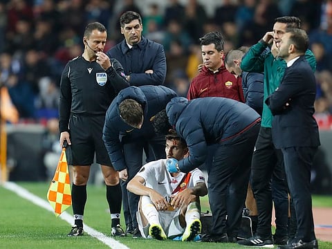 Roma's Lerenzo Pellegrini, bottom, receives first aid after was hit by an object thrown by fans.