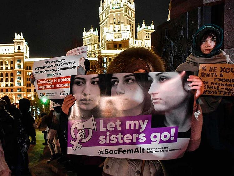 Demonstrators holding a placard with images of three Khachaturyan sisters 