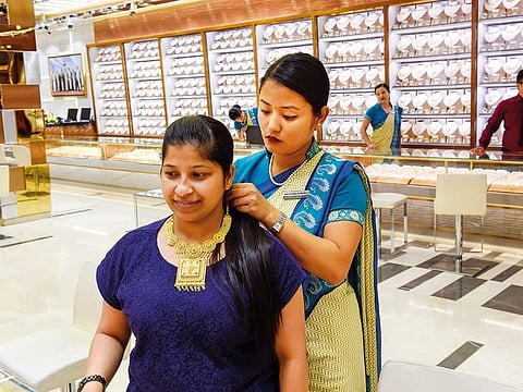 A young shopper tries on a traditional necklace at Kanz Jewels in Meena Bazaar. Reports suggest Gen Z is less likely than previous generations in buying gold jewellery.