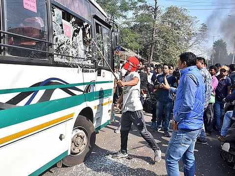 A protester breaks a glass window of a city bus during a strike called by AACSU in protest against the government's Citizenship Amendment Bill, in Guwahati on December 9, 2019.  