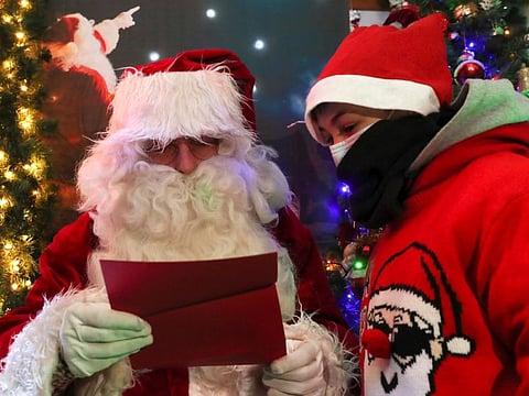 A man dressed as Santa Claus (Father Christmas) interacts with a child in a house that belongs to Serge Hennebel, nicknamed "Elf Serge" and is transformed into a Christmas village adorned with hundreds of lights, in Hamme-Mille, Belgium December 7, 2019  REUTERS/Yves Herman