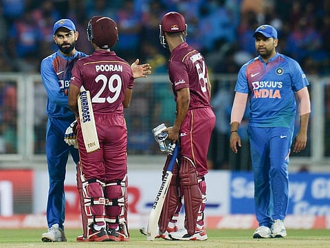 West Indies cricketer Lendl Simmons (R) and Nicholas Pooran (C) speak with Indian cricket captain Virat Kohli (L) after winning  the second T20 international cricket match at the Greenfield International Stadium in Thiruvananthapuram on December 8, 2019.    