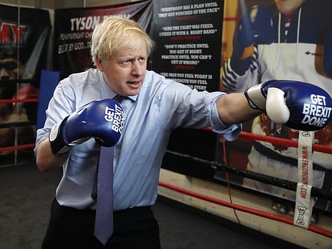 In this Tuesday, Nov. 19, 2019 file photo Britain's Prime Minister Boris Johnson poses for a photo wearing boxing gloves during a stop in his General Election Campaign trail at Jimmy Egan's Boxing Academy in Manchester, England. 