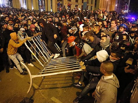 Anti-government protesters remove the fences that was divided between them and the riot police, during a protest near the parliament square, in downtown Beirut, Lebanon, Sunday, Dec. 15, 2019. 