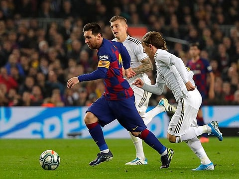 Barcelona's Lionel Messi, left, vies for the ball with Real Madrid's Luka Modric, right.