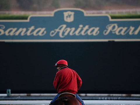an outrider waits by the track as horses train for the Breeders' Cup horse races at Santa Anita Park in Arcadia, Calif.