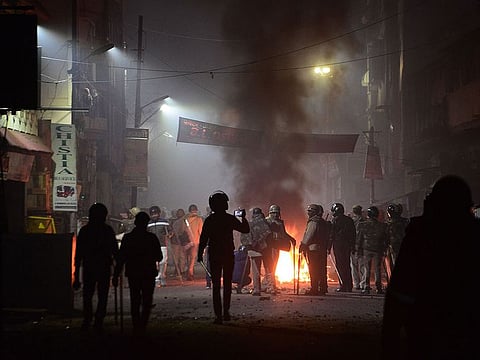 Firefighters and police personnel stand next to burning objects set on fire during demonstrations against India's new citizenship law in Kanpur on December 21, 2019. 