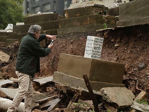 Beirut : A man takes a picture of graves in a Jewish cemetery damaged from heavy rains in the Sodeco area of Beirut, Lebanon, Thursday, Dec. 26, 2019. A heavy storm hit Lebanon with heavy rain and strong winds causing an old wall to collapse in the country's only Jewish cemetery, causing damage to several tombstones. Lebanon once had a thriving Jewish community, but the various Arab-Israeli wars and Lebanon's own 1975-90 civil war caused waves of emigration and almost none are left in the country today