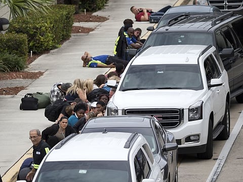 In this January 6, 2017 file photo, people take cover outside Fort Lauderdale–Hollywood International Airport, Florida, after a shooter opened fire inside a terminal of the airport, killing several people and wounding others before being taken into custody. 