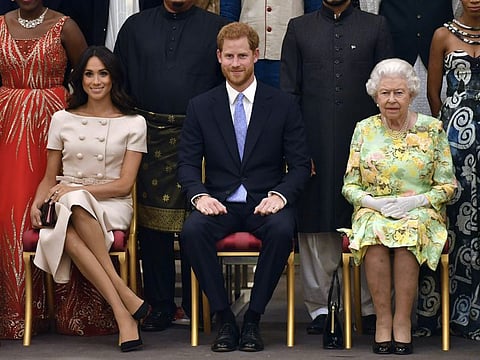 In this Tuesday, June 26, 2018 file photo Britain's Queen Elizabeth, Prince Harry and Meghan, Duchess of Sussex pose for a group photo at the Queen's Young Leaders Awards Ceremony at Buckingham Palace in London.
