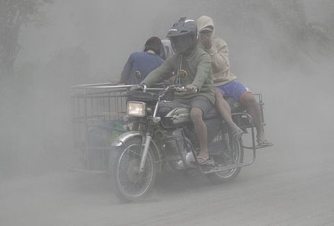 A family rides their motorcycle through clouds of ash as they evacuate to safer grounds as Taal volcano erupts in Tagaytay, Cavite province, southern Philippines on Monday. Red-hot lava is gushing from the volcano after a sudden eruption of ash and steam that forced residents to flee and shut down Manila’s airport, offices and schools.