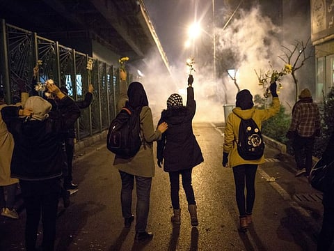 Protesters hold flowers as tear gas fired by police rises at a demonstration in front of Amir Kabir University in Tehran, Iran, to remember victims of a Ukrainian airplane shot down by an Iranian missile