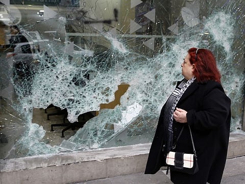 A woman looks at the broken glass of Bank of Beirut that was smashed by anti-government protesters in Beirut, Lebanon, Wednesday, Jan. 15, 2020. Banks in Hamra trade street were badly damaged after a night that witnessed clashes between anti-government protesters and Lebanese riot police.