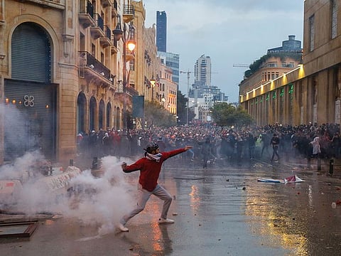 A demonstrator throws a tear gas canister during a protest in Beirut. The the situation in Lebanon is similar to that in many Arab countries, such as Iraq and Yemen, where militias have confiscated state institutions, including the agencies responsible for the economy.