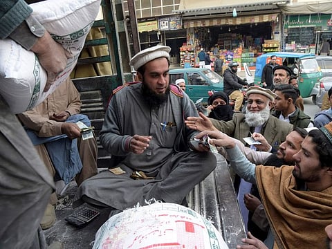 Local residents buy wheat flour sacks at government's control price along a a street in Peshawar on Monday. Pakistan's Economic Coordination Committee has approved a proposal to import 300,000 tons of wheat to overcome a nationwide shortage that had dramatically raised prices of the food staple.