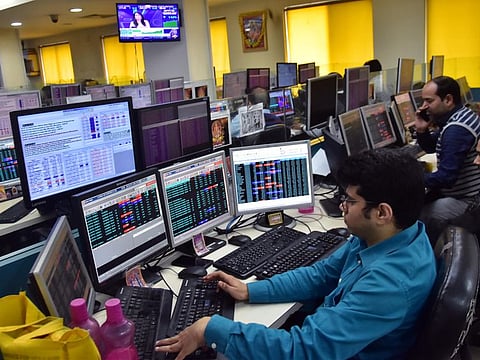 Traders work on the floor as Sensex 