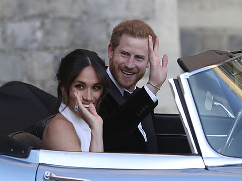 FILE - In this Saturday, May 19, 2018 file photo the newly married Duke and Duchess of Sussex, Meghan Markle and Prince Harry, leave Windsor Castle in a convertible car after their wedding in Windsor, England, to attend an evening reception at Frogmore House, hosted by the Prince of Wales. Prince Harry and Meghan Markle are to no longer use their HRH titles and will repay £2.4 million of taxpayer's money spent on renovating their Berkshire home, Buckingham Palace announced Saturday, Jan. 18. 2020. (Steve Parsons/pool photo via AP, File)