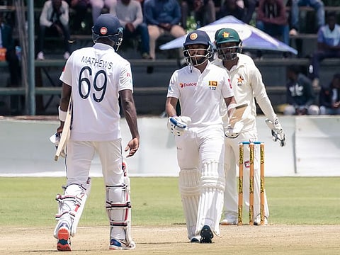 Sri Lanka's Kusal Mendis celebrates after scoring a half-century with his skipper Angelo Mathews during the third day of the first Test against Zimbabwe.