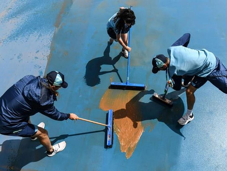 Workers attempt to clear mud off the courts at the Australian Open in Melbourne