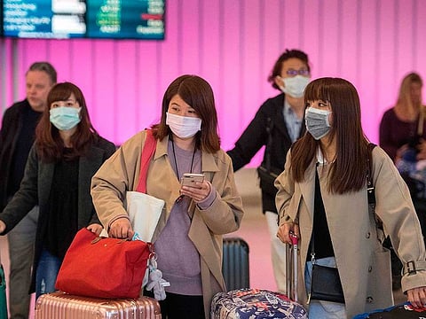 Passengers wear protective masks to protect against the spread of the Coronavirus as they arrive at the Los Angeles International Airport, California, on January 22, 2020.  