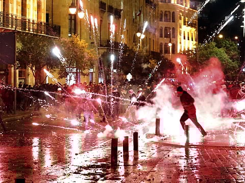 Lebanese protesters throw firecrackers at riot police during a demonstration against the new government, near Parliament Square, in Beirut on January 22, 2020.