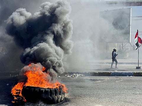 An Iraqi demonstrator walks past burning tires as they block a road during the ongoing anti-government protest in Nassiriya, Iraq January 27, 2020. 