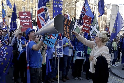 A supporter of Britain's departure from the European Union, at right, holds a placard up in front of supporters of remaining in the EU, including Stop Brexit Man, Steve Bray, with his foghorn, outside Parliament in London on February 27, 2019. Britain is finally due to leave the EU on January 31, 2020 after 47 years of membership.