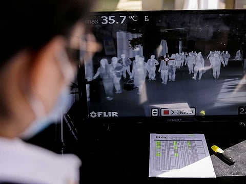 Airport personnel monitor a thermal scanner as passengers arrive at the Ninoy Aquino International Airport in Pasay, Philippines.
