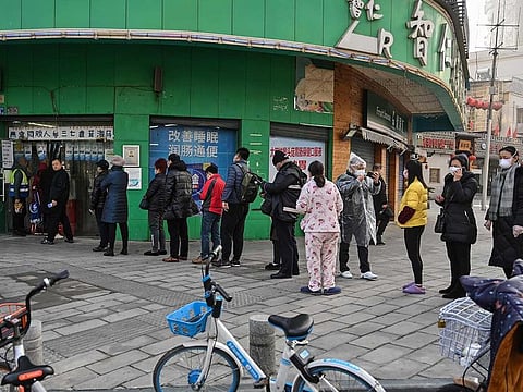 People wearing protective facemasks are seen next to a pharmacy in Wuhan, in Hubei province, on January 30, 2020. So far 170 people have been killed by the virus since it emerged from a market in Wuhan, and more than 7,700 people have been sickened. 