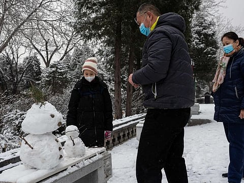A family wearing protective facemasks to prevent the spread of the SARS-like virus builds a snowman at the Jingshan park after a snowfall in Beijing on February 2, 2020. A virus similar to the SARS pathogen has killed more than 300 people in China and spread around the world since emerging in a market in the central Chinese city of Wuhan. / AFP / NICOLAS ASFOURI